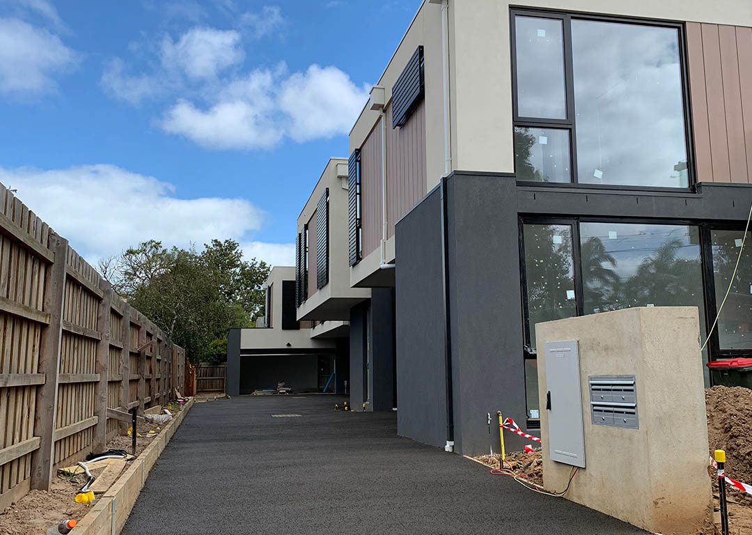 Permeable concrete driveway in front of modern residential buildings.