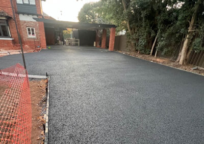 Newly paved permeable concrete driveway in front of a brick home.