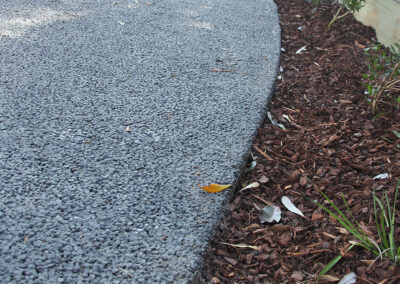 Close-up of a permeable concrete edge alongside a mulched garden bed.