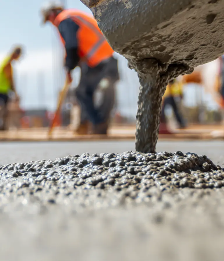 Professional concrete placement operation showing fresh concrete being poured with construction crew and reflective surface