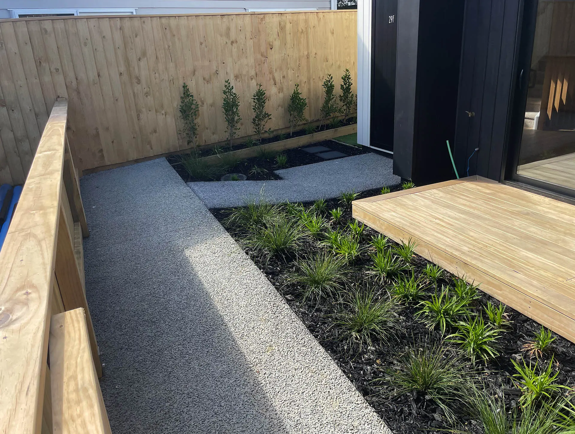 Curved concrete pathway around a house with surrounding greenery.